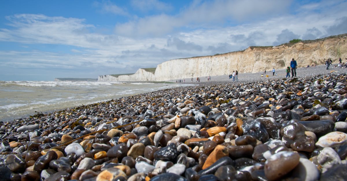 Scenic view of a pebble beach and white cliffs under a blue sky in England.
