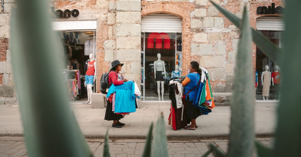 Colorful street scene in Oaxaca featuring local vendors selling clothing near a boutique.