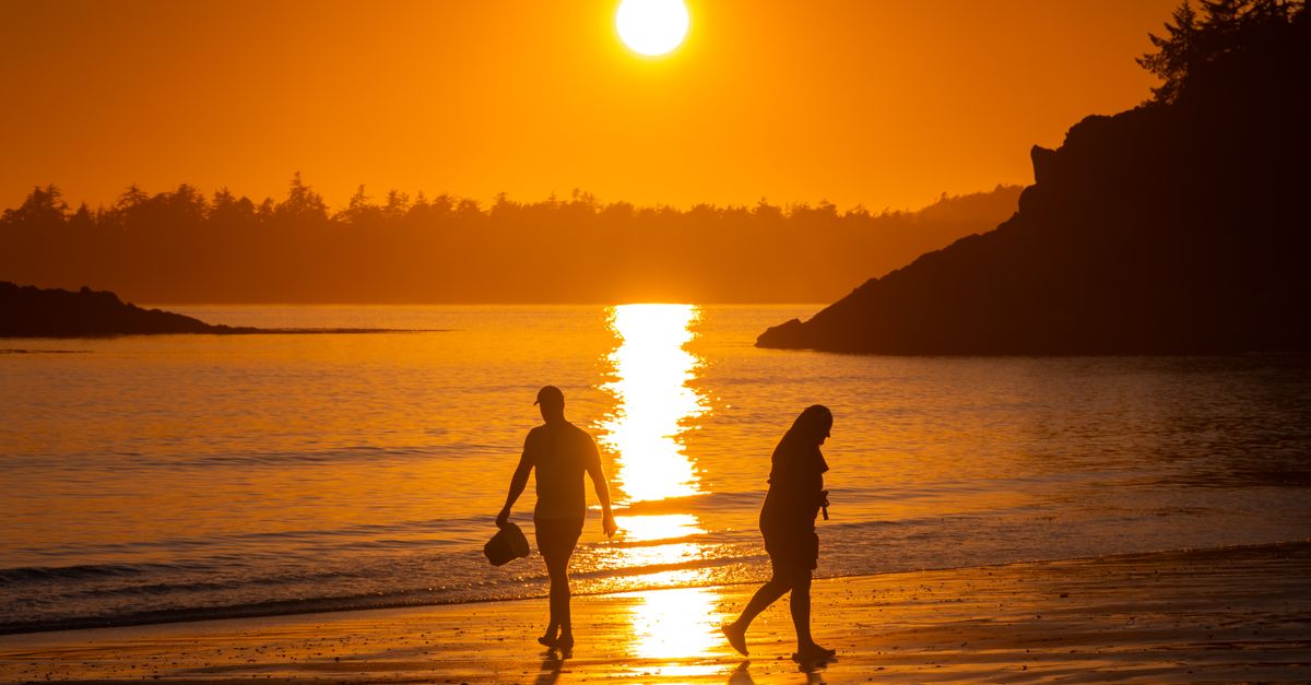 Gorgeous Tofino beach scene with silhouettes against a vibrant sunset reflection on the water.