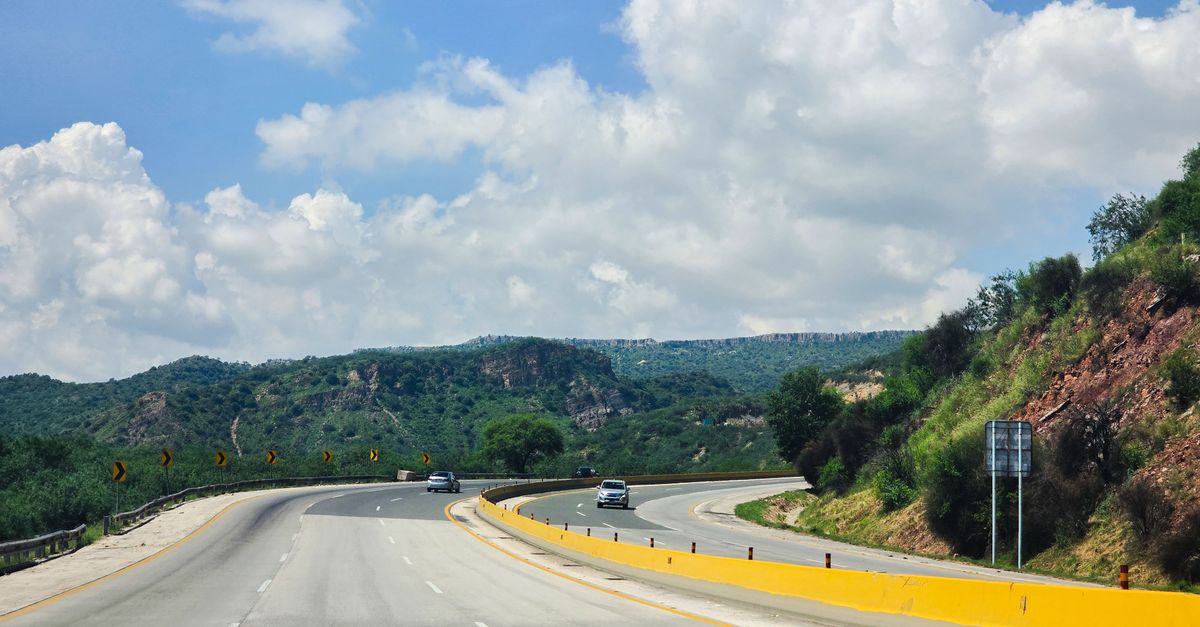 A picturesque highway curve through green hills under a bright sky, ideal for travel and nature themes.