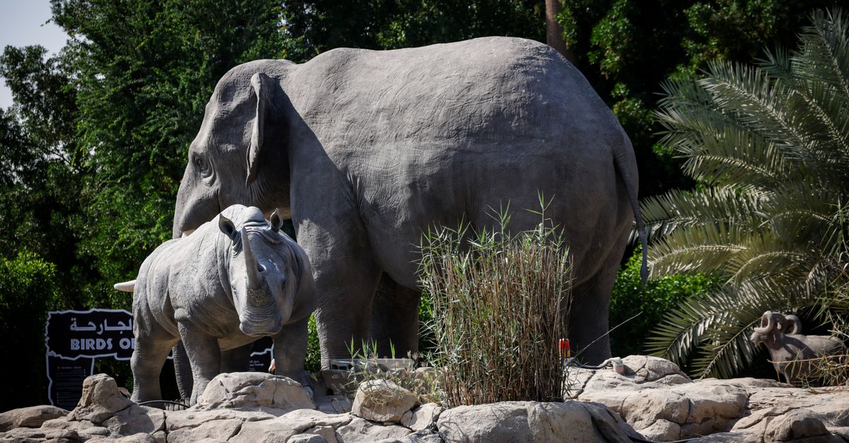 Elephant and rhino stone statues in a lush, outdoor environment.