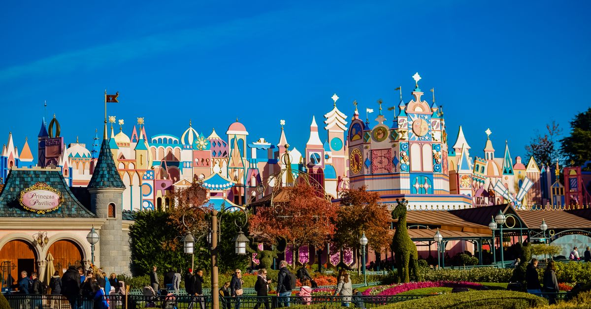Colorful Disneyland Paris scene showcasing iconic architecture and bustling visitors under a clear blue sky.