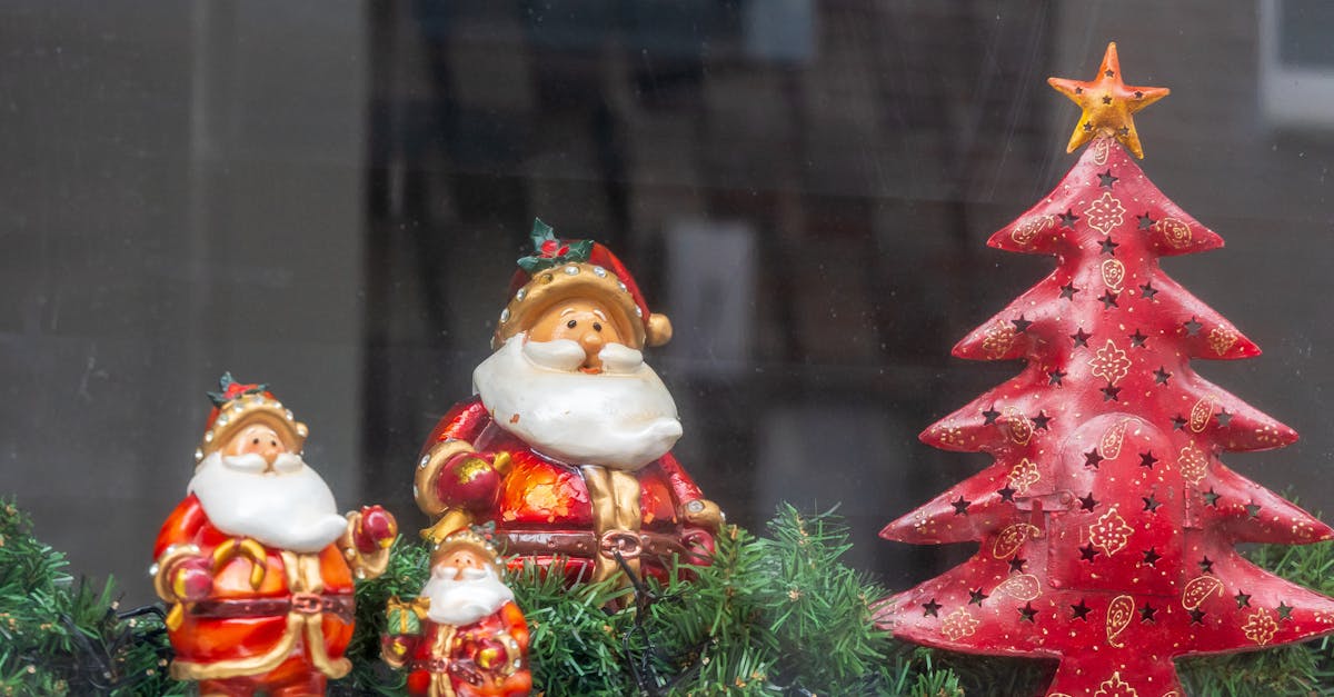 Adorable ceramic Santa Claus figurines beside a decorative red Christmas tree.