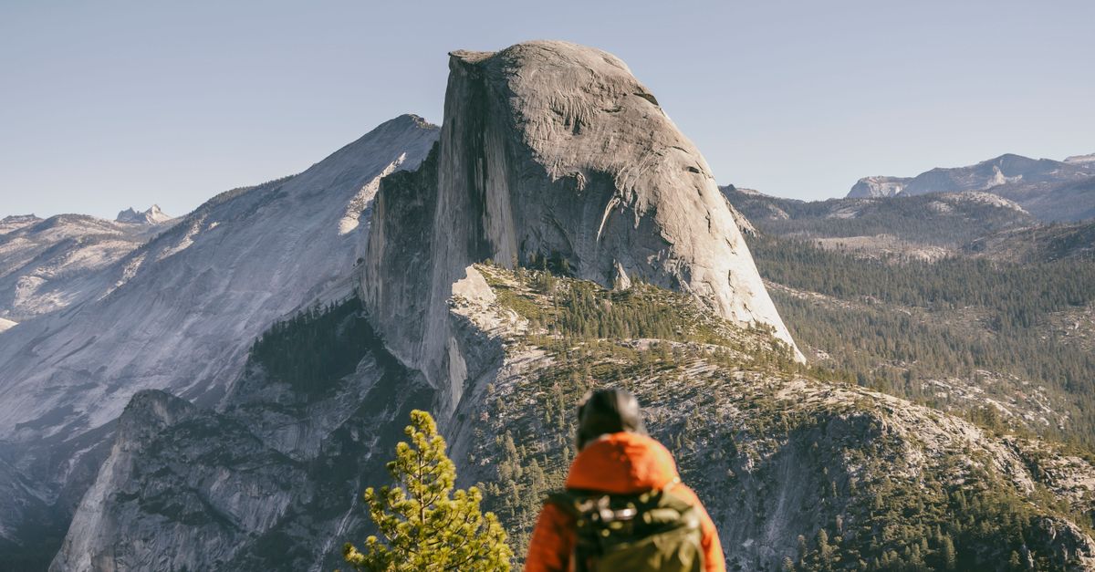Hiker admires the majestic view of Half Dome in Yosemite National Park during fall.