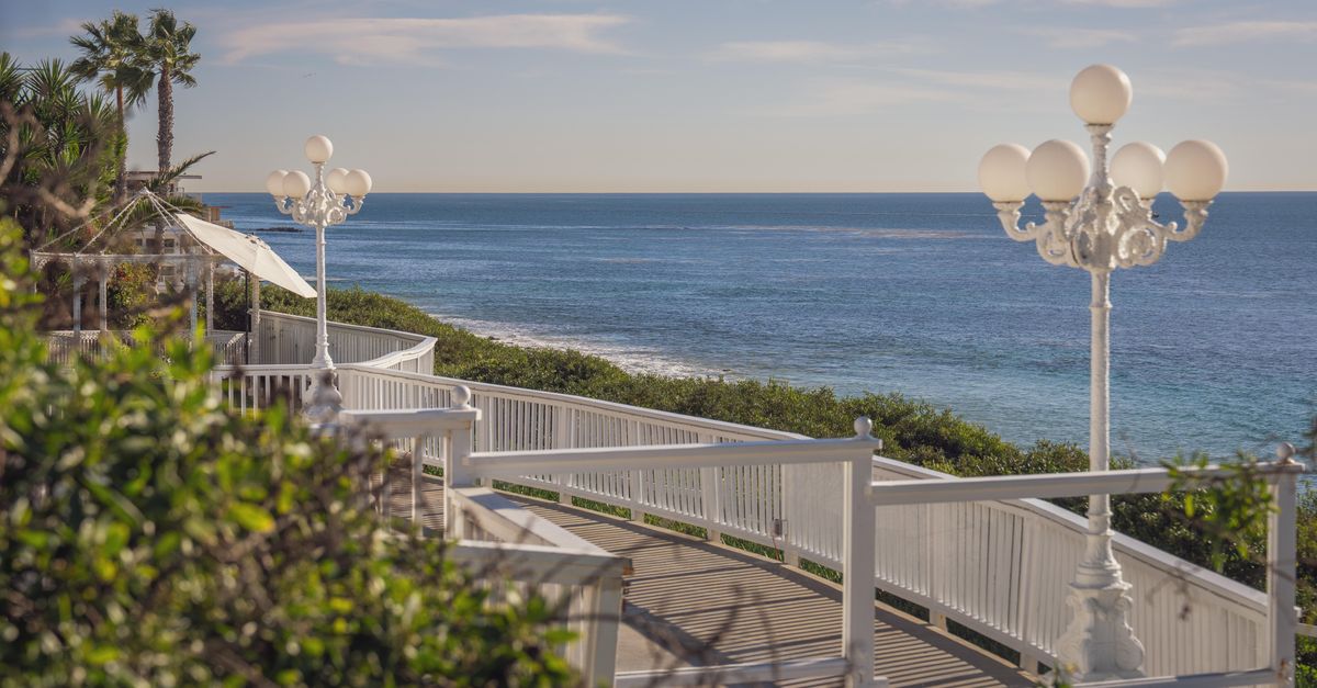 Serene coastal boardwalk overlooking the ocean with vintage street lamps and lush greenery.