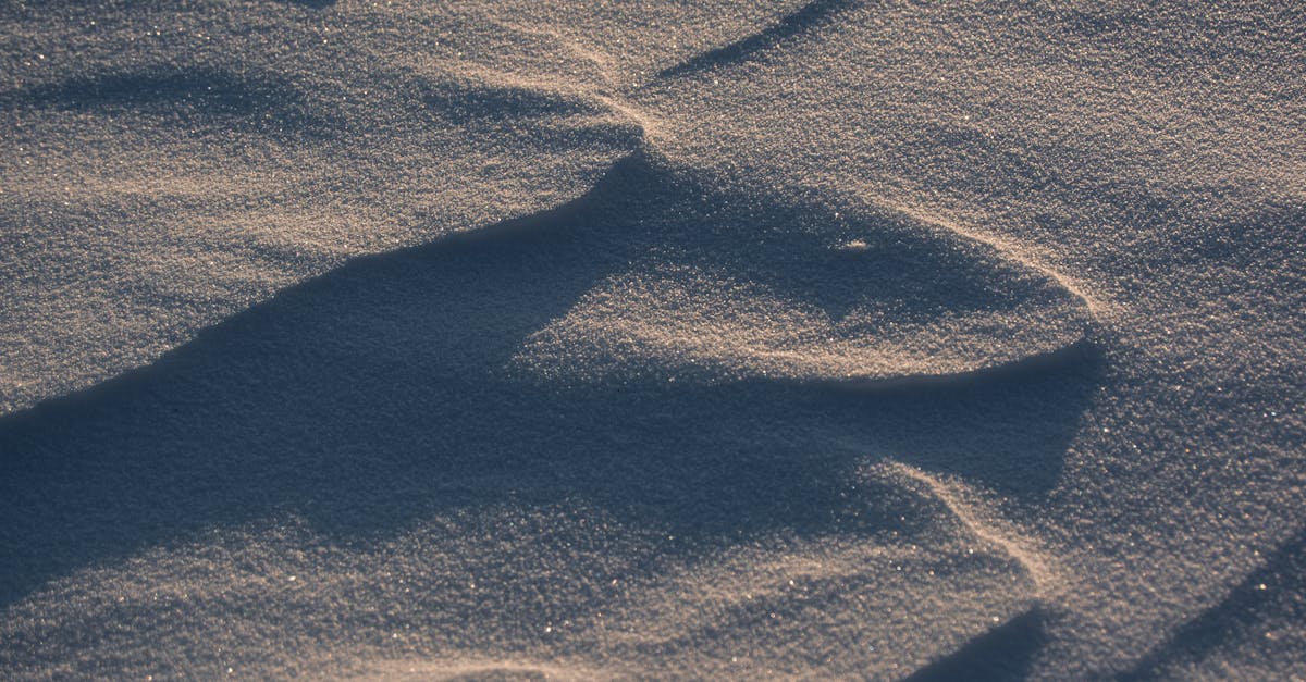 Close-up of a textured snow surface with morning shadows, creating an abstract pattern.