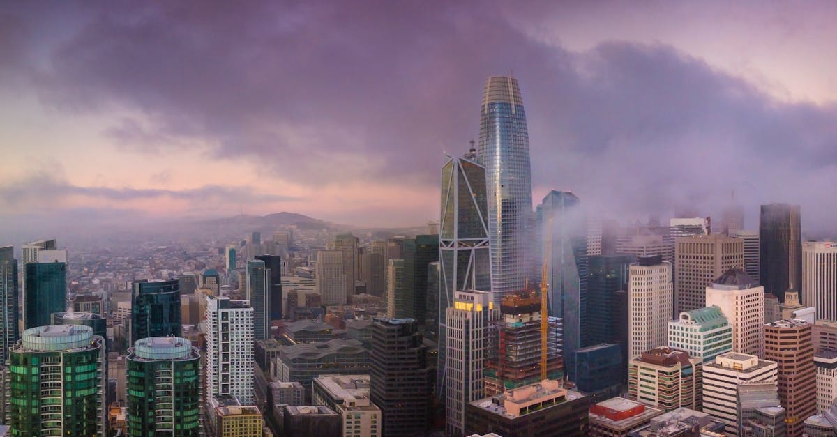 Aerial view of San Francisco's skyline at sunset with iconic skyscrapers and dramatic clouds.