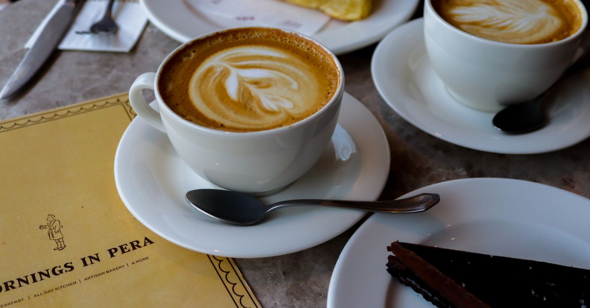 Warm cafe scene with cappuccinos, chocolate cake, and croissant, perfect for a cozy morning.