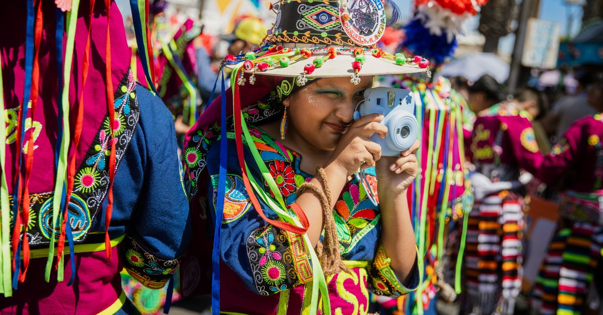 A vibrant Tinku dancer capturing moments at Arica's lively carnival under a sunny sky.