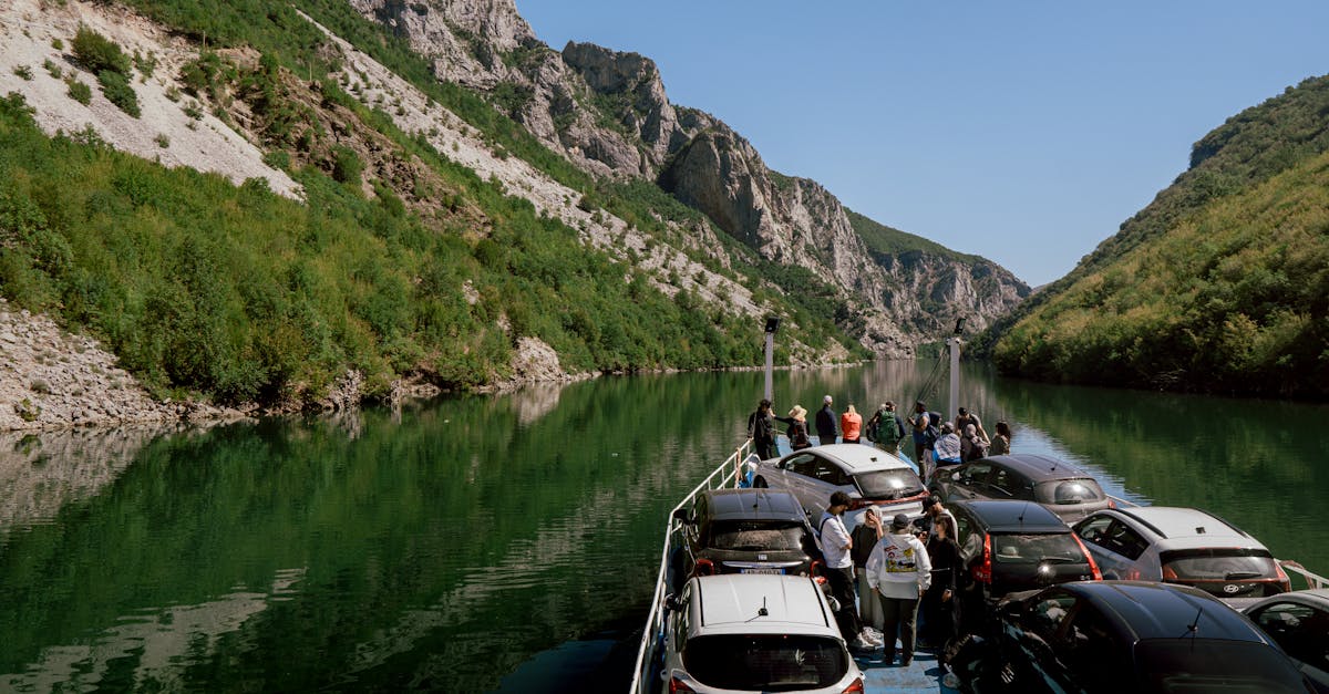 Scenic ferry journey on Koman Lake in Albania, transporting cars and travelers through breathtaking mountain landscapes.