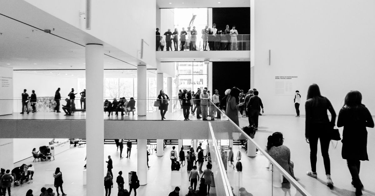 A dynamic black and white image of people in a modern museum setting.