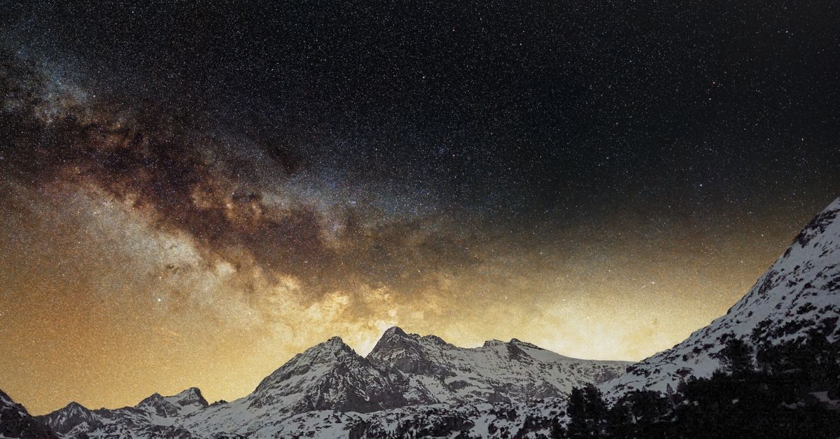 A breathtaking view of the Milky Way galaxy over snow-capped mountains, captured on a clear night.