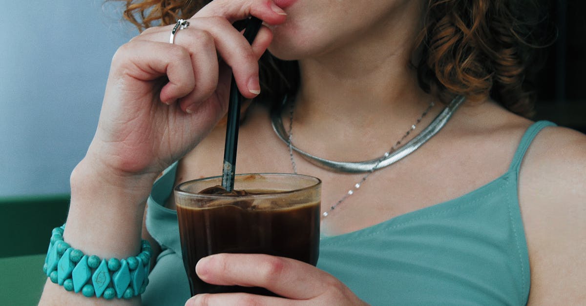 Close-up of a woman sipping iced coffee, wearing silver jewelry and turquoise bracelet.