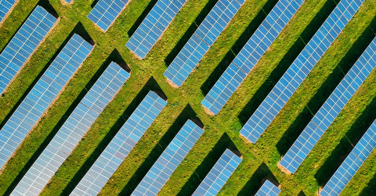 High-angle aerial shot of solar panels in a lush green field, located in Rockbeare, UK.