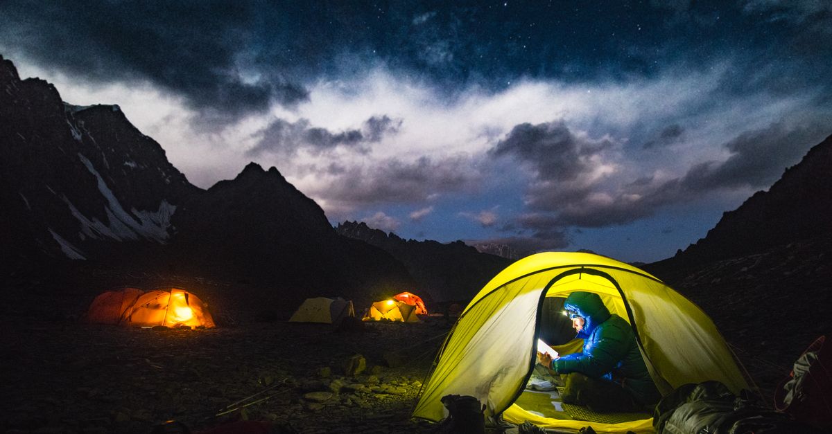 Scenic night camping in Badakhshan, Afghanistan with illuminated tents under a starry sky.