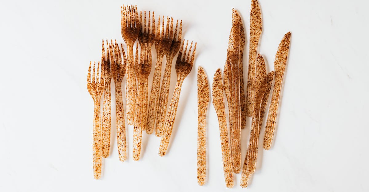 Top view of heap disposable plastic forks folded chaotically on white surface placed near bunch disposable plastic knives