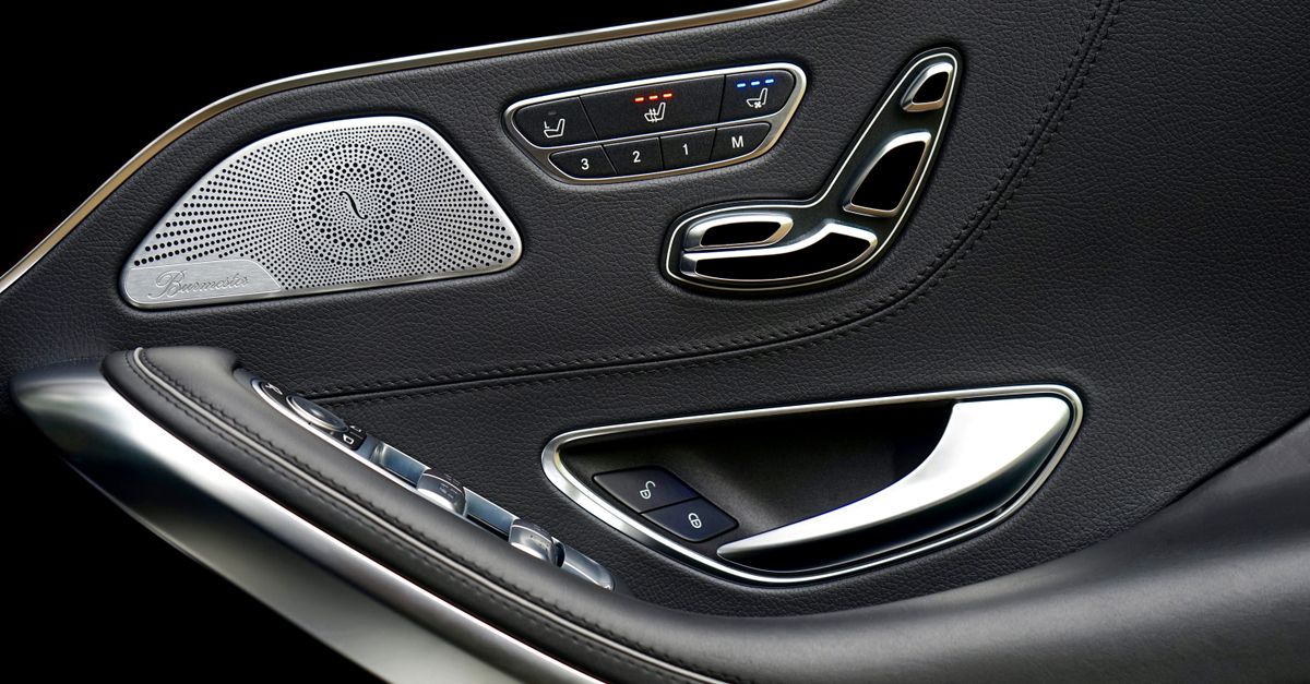 Close-up of a luxury car's interior door panel showcasing sleek design, buttons, and speaker.