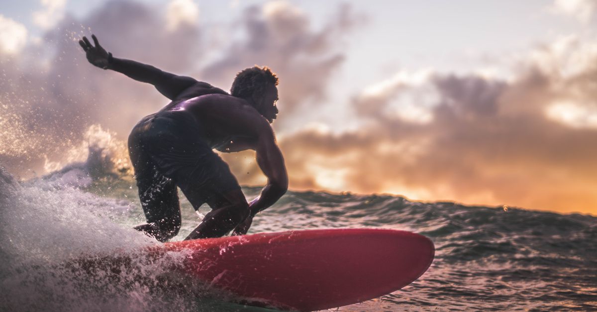 A surfer rides the waves during a vibrant sunset, showcasing an exhilarating ocean adventure.