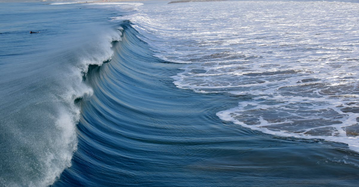 Picturesque view of blue rippled sea with foamy waves near coast with houses in stormy weather