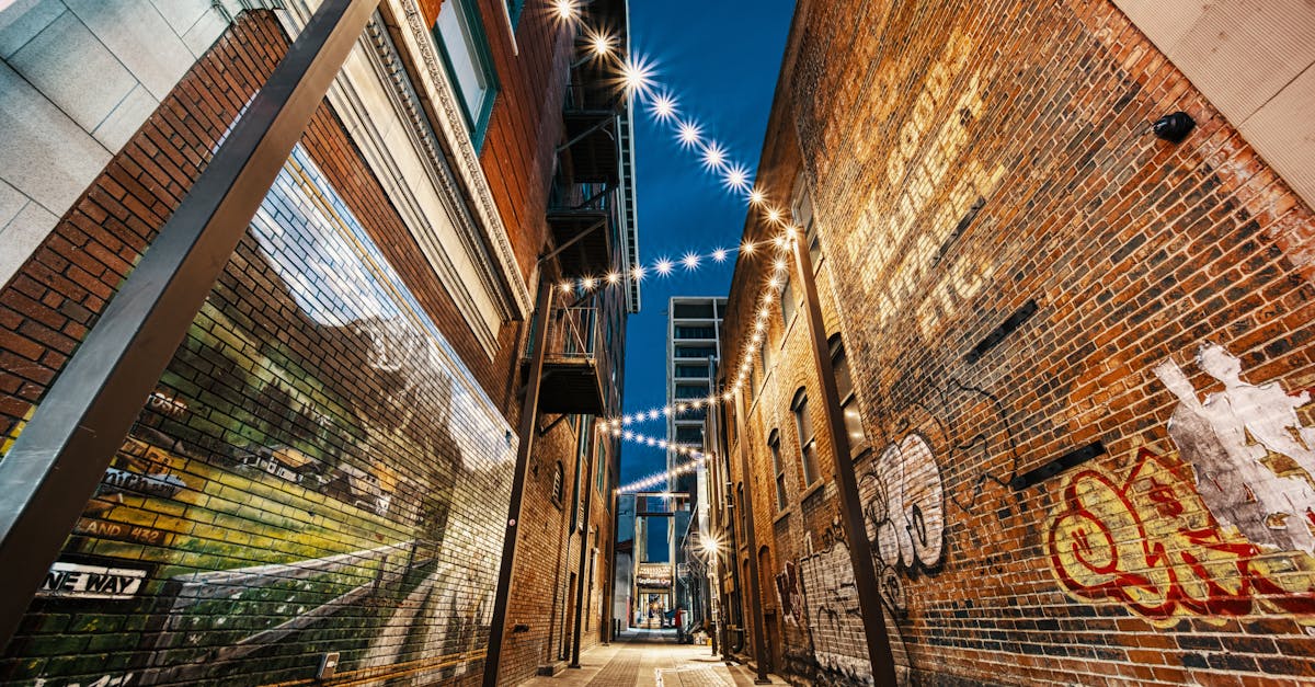 Perspective view of narrow empty highlighted street with graffiti on brick old walls