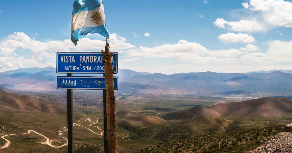 Scenic vista in Jujuy, Argentina with vibrant mountains and waving flag under a clear sky.