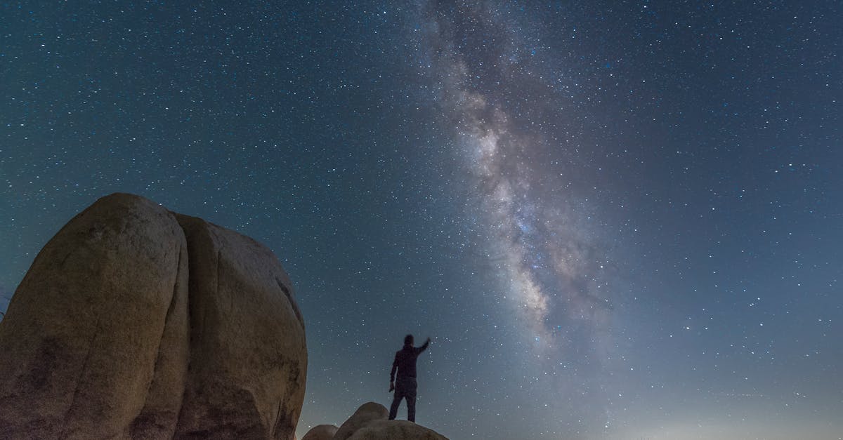 A person silhouetted against the Milky Way starry night in a desert landscape.