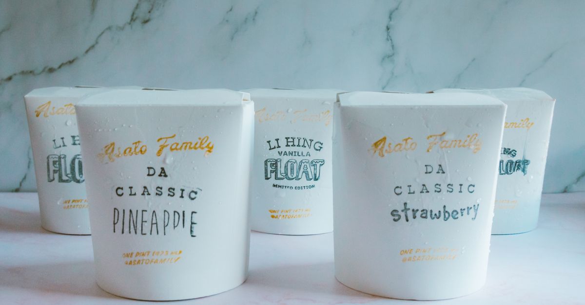 Delicious assortment of ice cream flavors in elegant paper tubs on a marble surface.