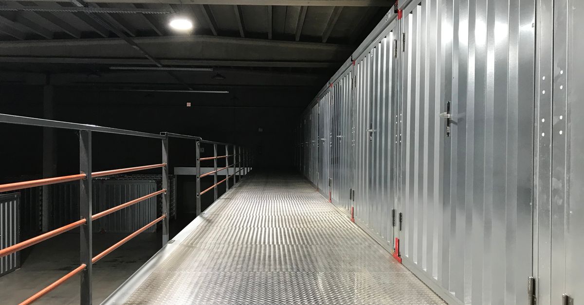 Empty industrial hallway with steel lockers and railing in a warehouse.