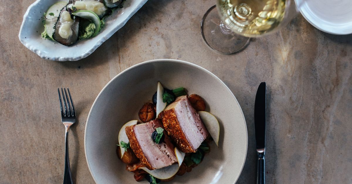 Elegant flat lay of a gourmet pork dish paired with white wine, perfect for dining aesthetics.
