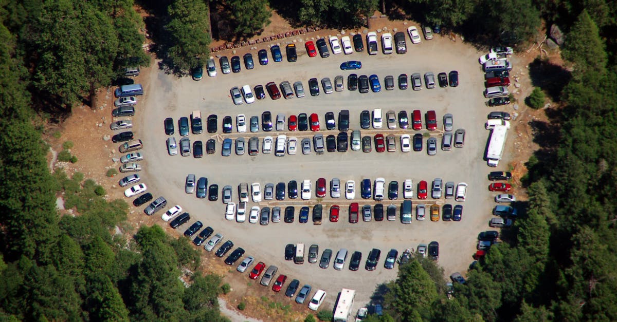Drone shot showing an organized parking lot full of vehicles surrounded by trees.