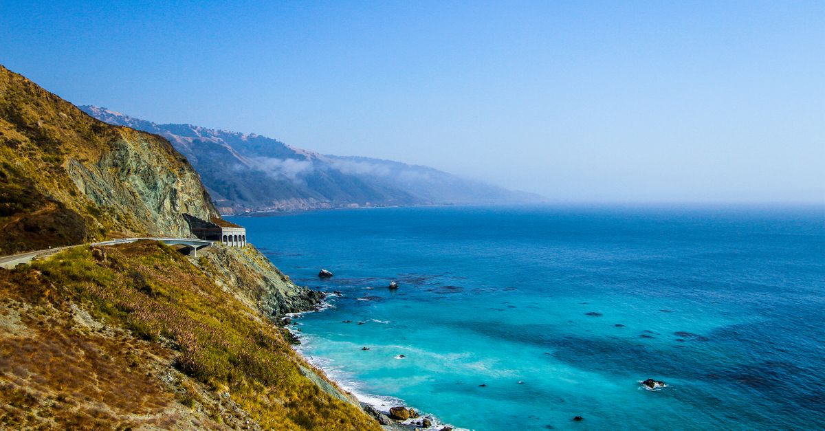 Breathtaking view of the Big Sur coastline with turquoise waters and rugged cliffs under a clear blue sky.