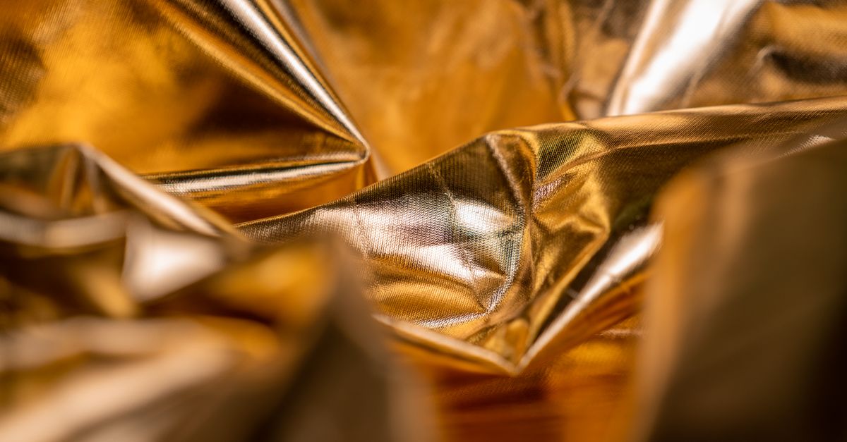 Close-up of crumpled golden metallic texture, focusing on glossy highlights.