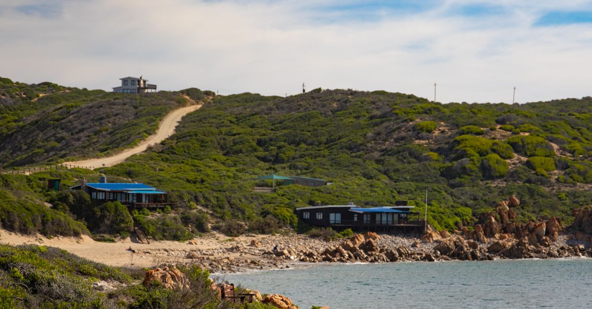 Beautiful coastal scene with beach houses, lush hills, and a serene ocean view.