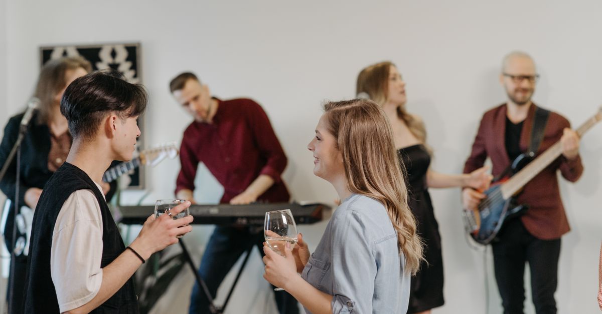 A group of friends enjoying a casual indoor home concert with live music and conversation.