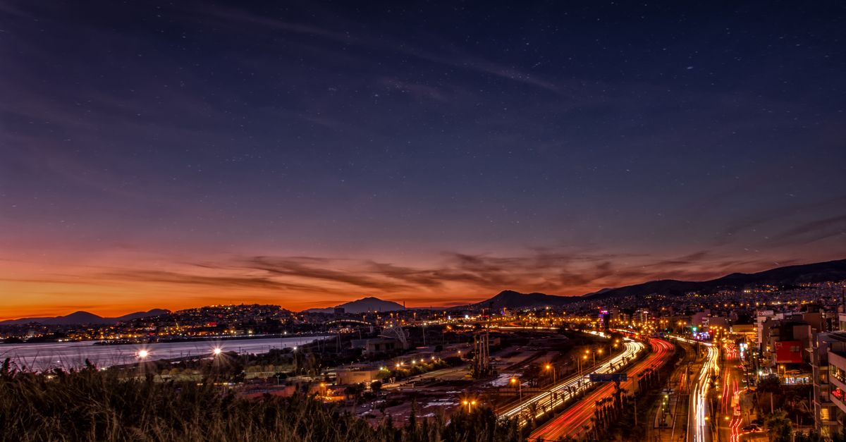 Stunning cityscape at dusk showcasing light trails, mountains, and a glowing skyline.