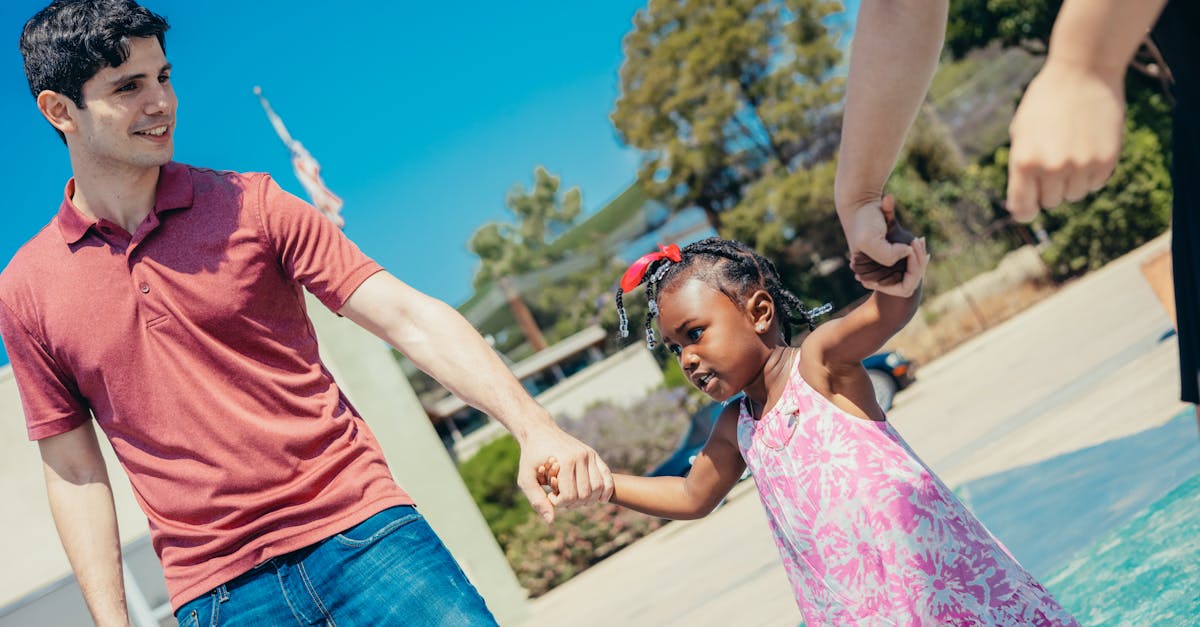 A father and daughter holding hands by the pool on a bright, sunny day outdoors. Family leisure time.