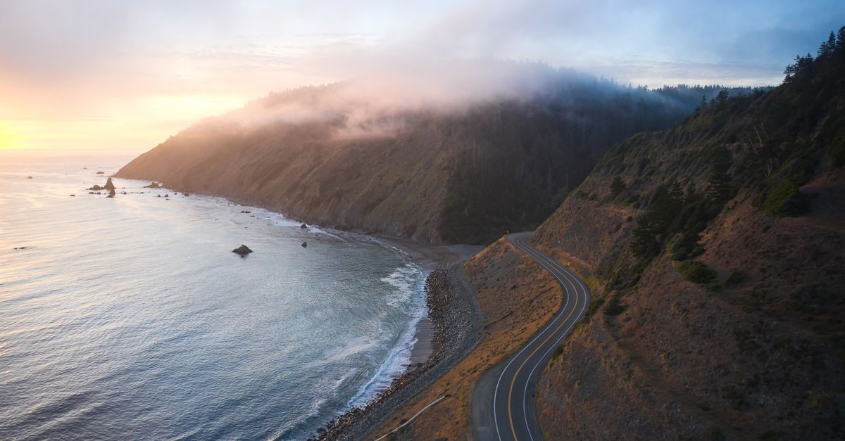 A breathtaking aerial view of a winding coastal road and ocean during sunset in Westport, California.