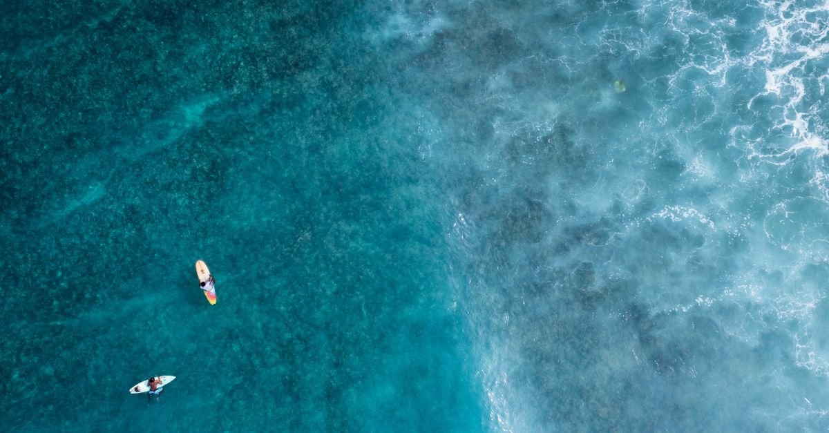 Stunning aerial shot of surfers navigating turquoise ocean waves, perfect for summer and adventure themes.