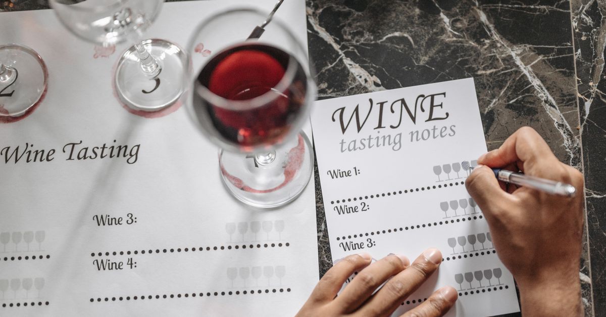 Close-up of wine tasting session with notes, glasses, and marble surface.