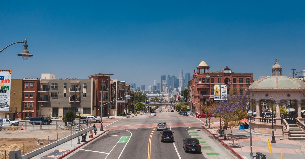 A vibrant city street with the Los Angeles skyline in the distance on a sunny day.