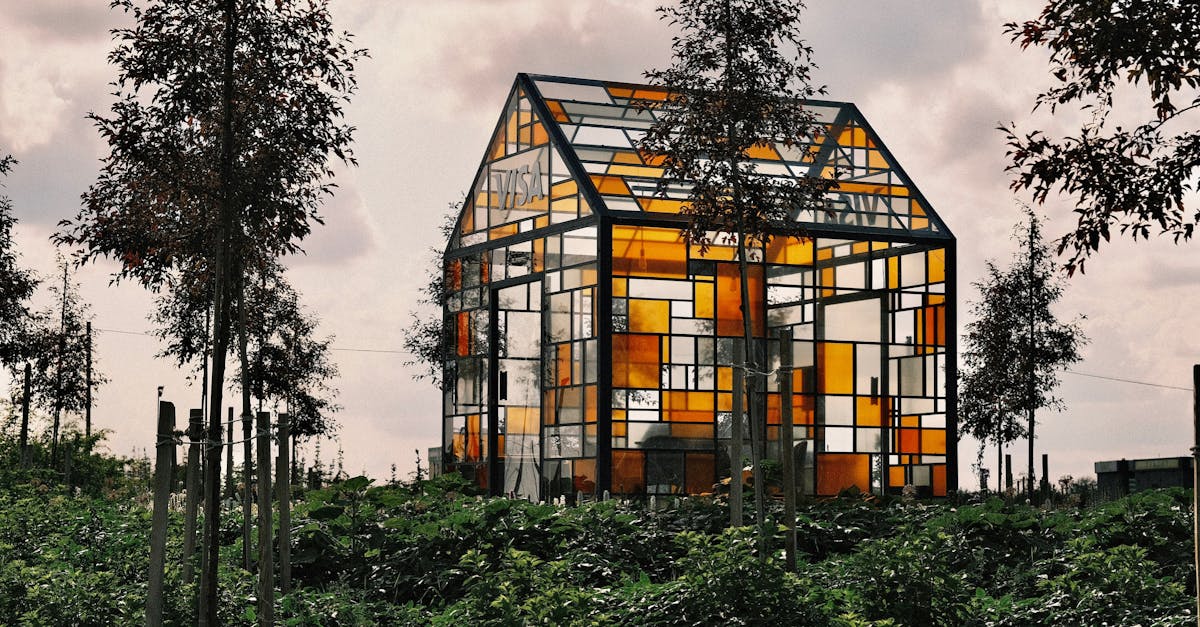 Colorful glass house amidst lush greenery, creating a unique landscape view.