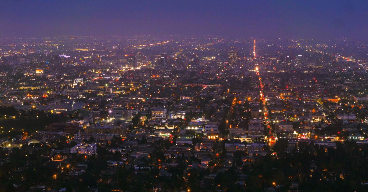 Vibrant city lights and urban sprawl photographed from above during nighttime, showcasing a bustling modern city.