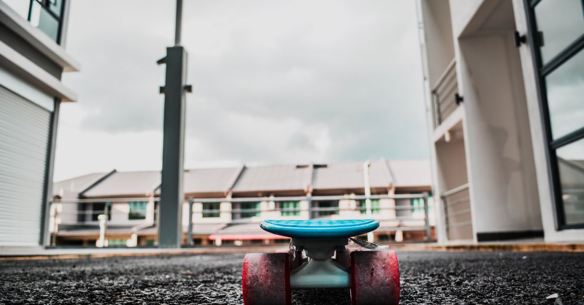 A skateboard rests on wet pavement capturing an urban city atmosphere with modern architecture.