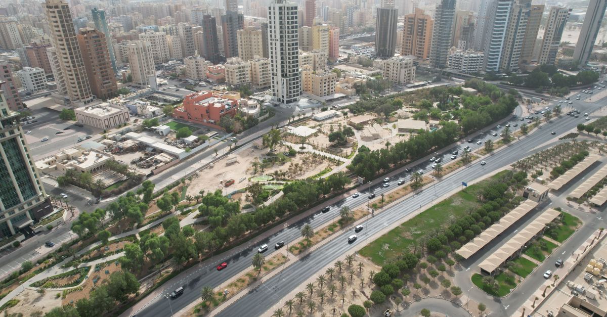 Aerial cityscape of Kuwait City with bustling roads and high-rises on a clear day.