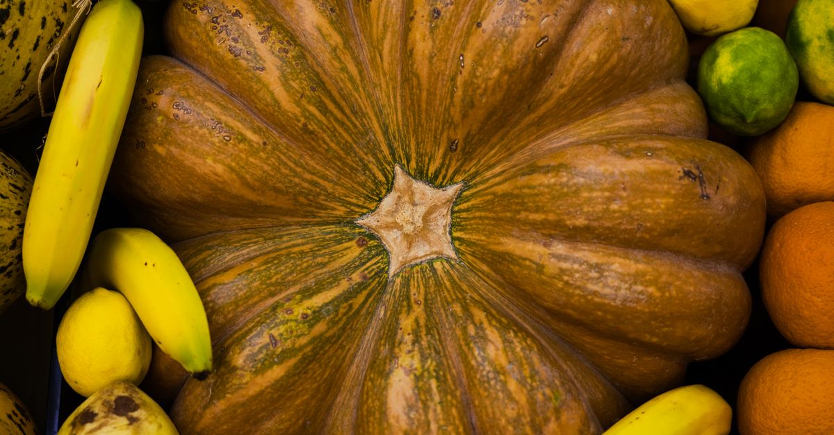 An overhead view of fresh fruits and a pumpkin, showcasing vibrant colors and textures.